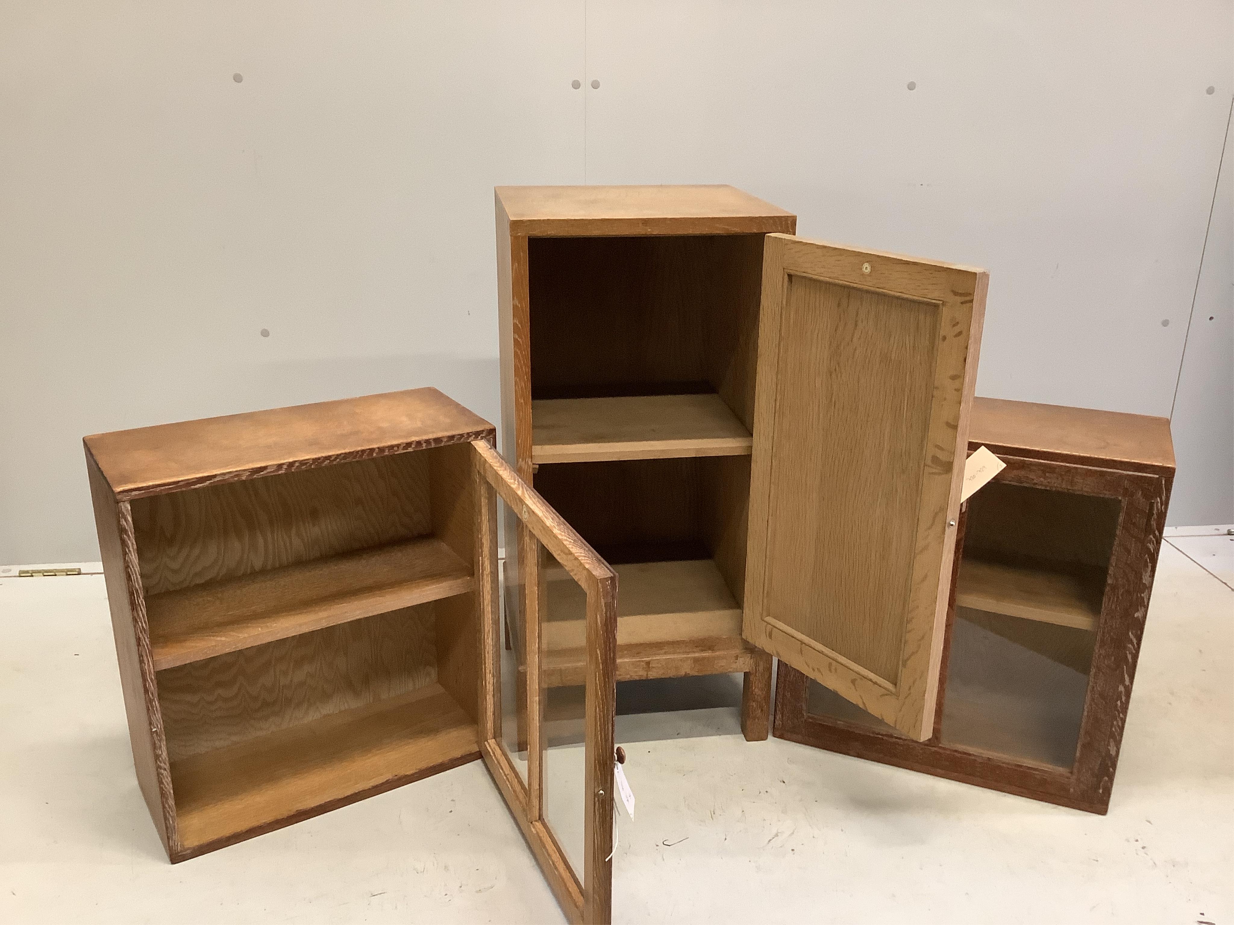 Heal & Son Ltd. A pair of weathered oak wall cabinets, width 45cm, depth 21cm, height 50cm together with a Heals oak bedside cupboard, width 36cm, height 76cm. Condition - fair to good